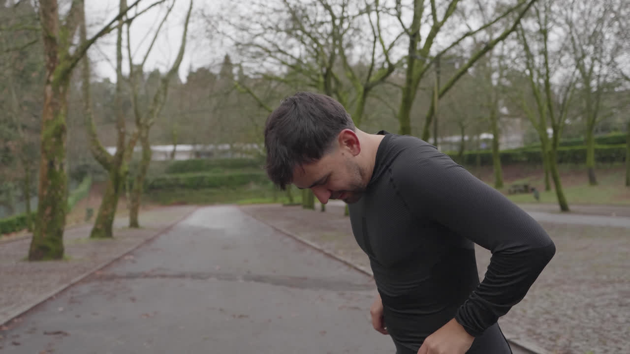Adult man preparing workout by adjusting strap on quiet outdoor path