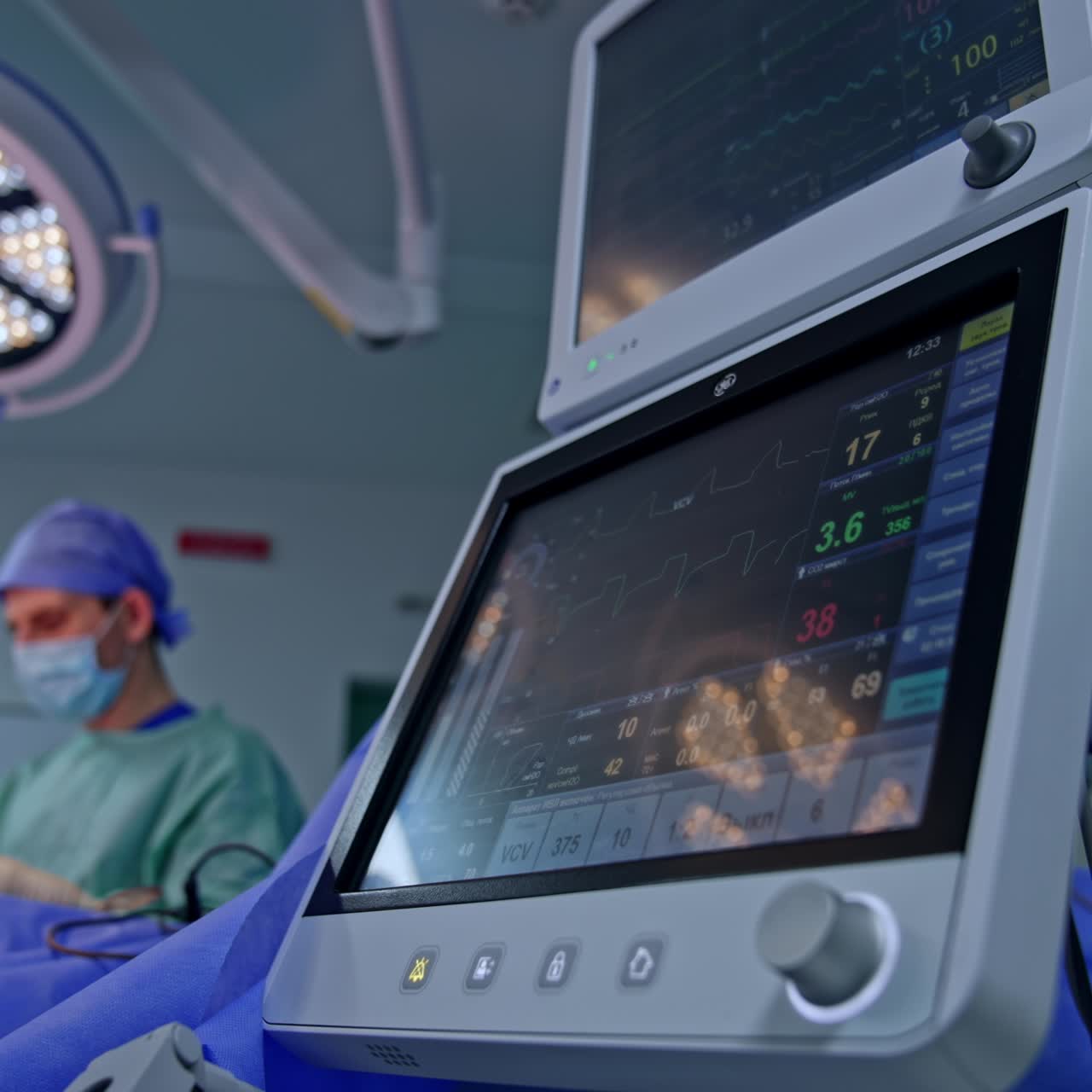 Lung ventilator equipment working in surgery room. Low angle view of the screens. Doctors work at operational table. Blurred backdrop