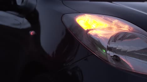 Detail-of-a-black-car-with-yellow-front-turn-signal-on