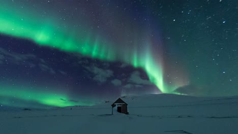 Magical-aurora-borealis-time-lapse-dancing-on-night-sky,-above-cabin,-Iceland