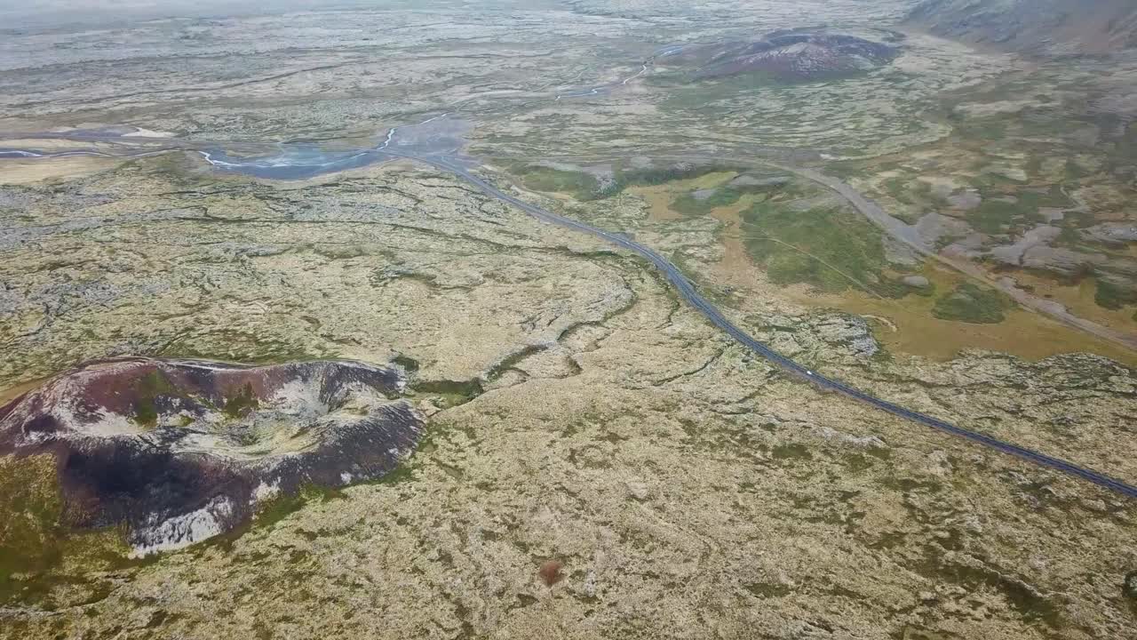 Expansive aerial view of Saxholl Crater in Iceland, showcasing volcanic formations, winding rivers, and lush mossy terrain, highlighting the region's unique geological and natural beauty