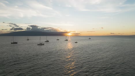 Vista-De-La-Puesta-De-Sol-De-La-Isla-Lanai-Desde-La-Playa-De-Lahaina,-Antena-Hacia-Atrás-Desde-Barcos-Anclados