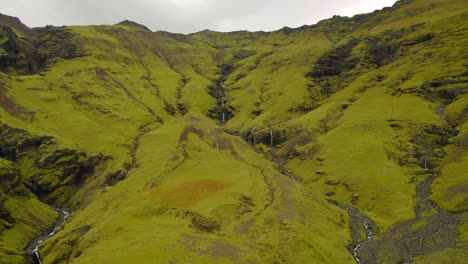 line of waterfalls flowing a volcanic green valley in south iceland