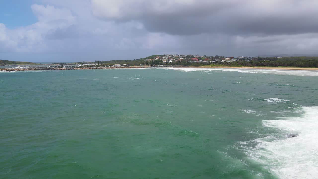 drone volando sobre el mar con olas rompiendo en la pequeña isla muttonbird - coffs harbour con cielo nublado en nsw, australia