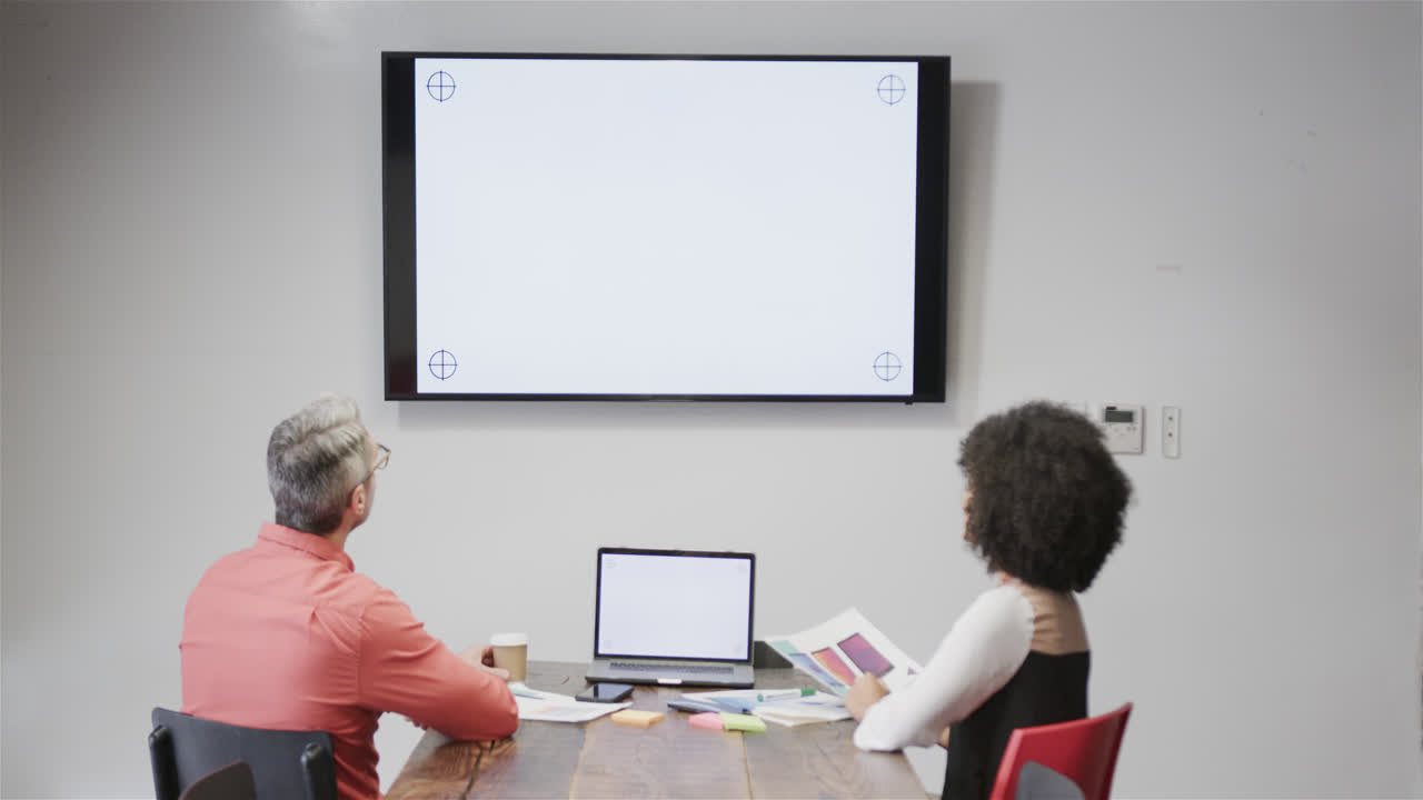 diversos colegas teniendo videoconferencia con portátil y monitor, espacio de copia en las pantallas, cámara lenta