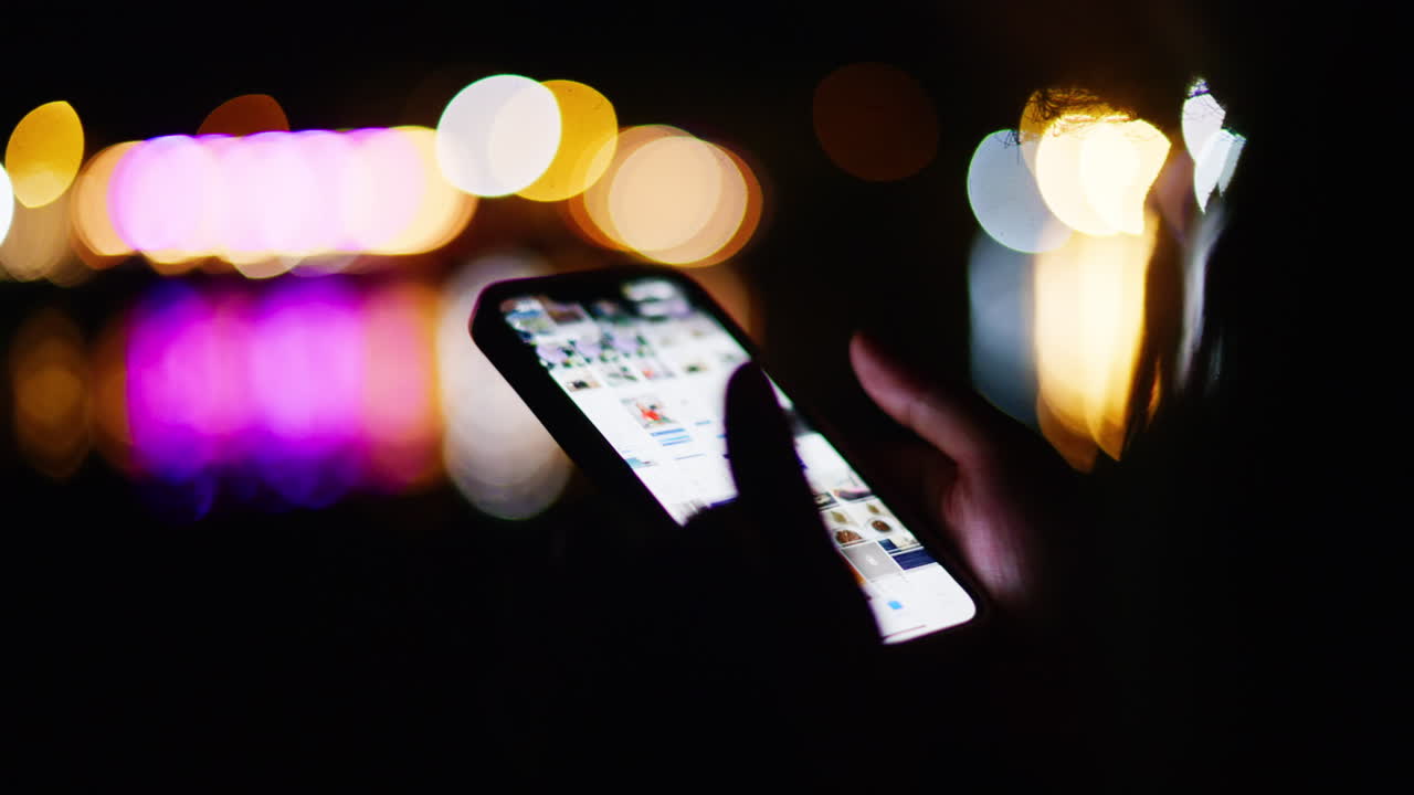 Woman scrolling on her phone on the beach at night