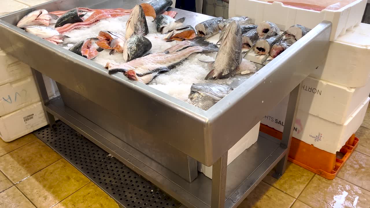 trozos de pescado cortados frescos en hielo en recipientes metálicos