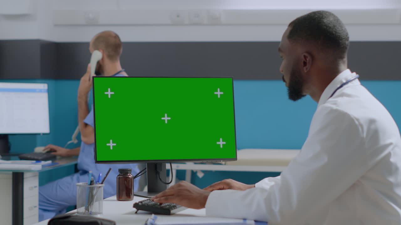 Læge, der arbejder ved computer med grøn skærm