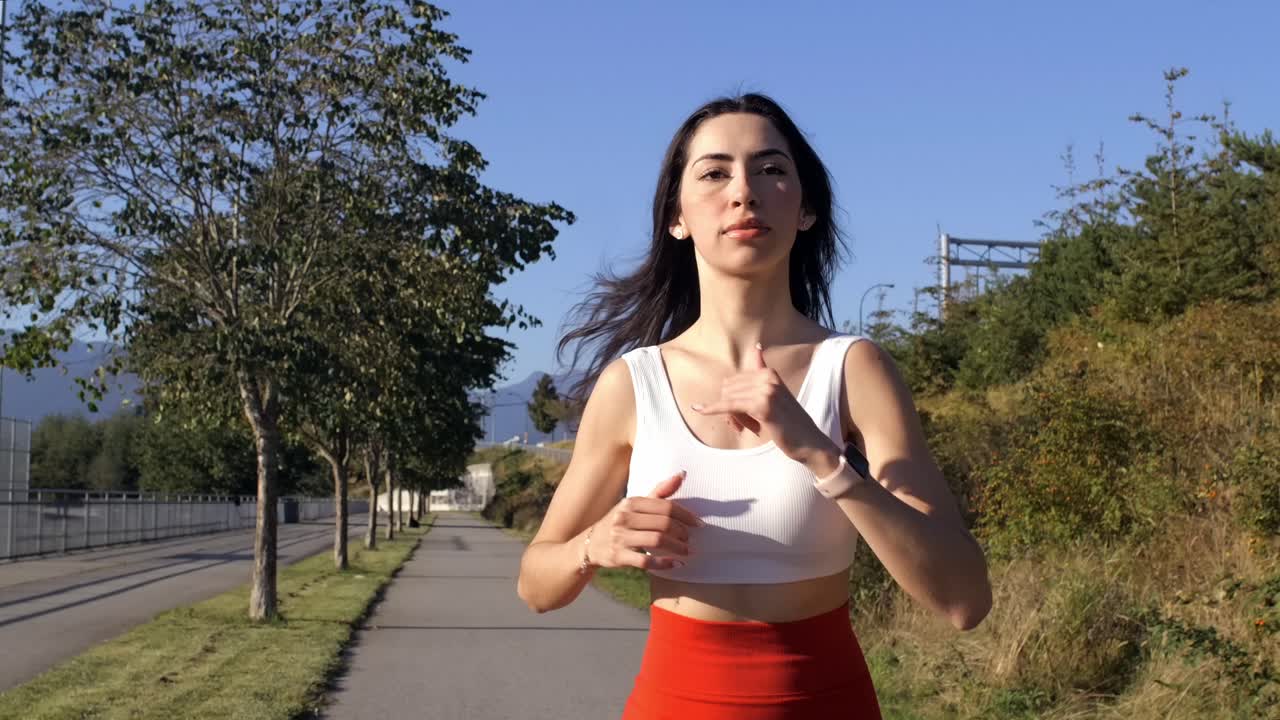 Front View of Athletic Woman Running Outdoors in the Sun - Slow Motion