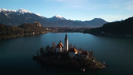 drone descends to reveal mountain landscape behind bled island, slovenia