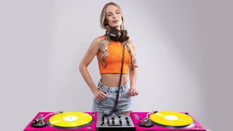 a pretty female dj dancing behind record turntables in orange top