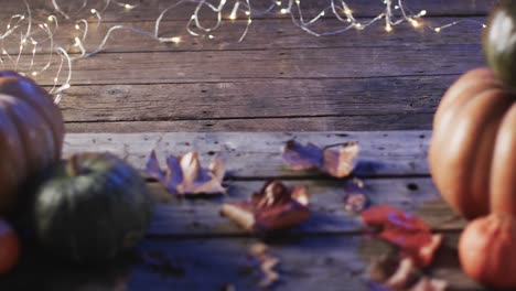 video of halloween pumpkins with leaves and copy space on wooden background