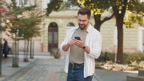 happy tourist young man using cellphone looking for search a way on map in navigator app on street