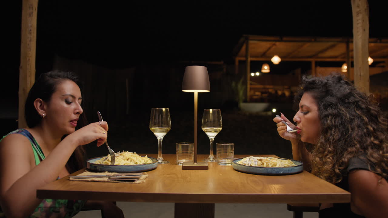 Two Friends Enjoying An Outdoor Dinner At The Restaurant In The Summer