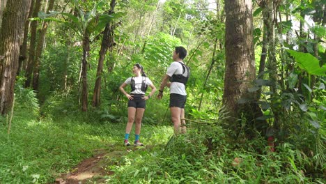 asian couple resting and talking during outdoor workout in forest trail