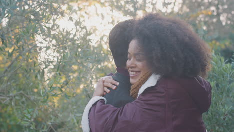 loving young couple meeting and hugging outdoors in fall or winter countryside against flaring sun