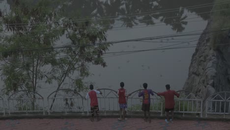 Niños-Con-Uniforme-De-Fútbol-Mirando-Ofertas-Y-Arrojando-Piedras-Al-Lago