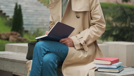 estudiante caucásica escribiendo en un cuaderno en el parque.