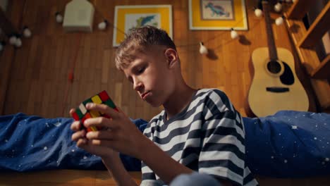 boy solving a rubik's cube in his bedroom