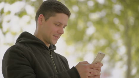 Fröhlicher-Junger-Mann,-Der-Im-Freien-Sein-Handy-Benutzt