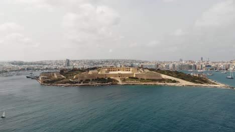 vista panorámica de la isla manoel rodeada por el paisaje marino de la ciudad de sliema en malta - toma aérea de órbita lenta
