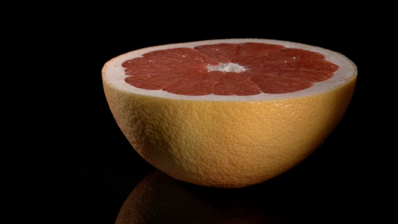Half a grapefruit close-up on a black background.