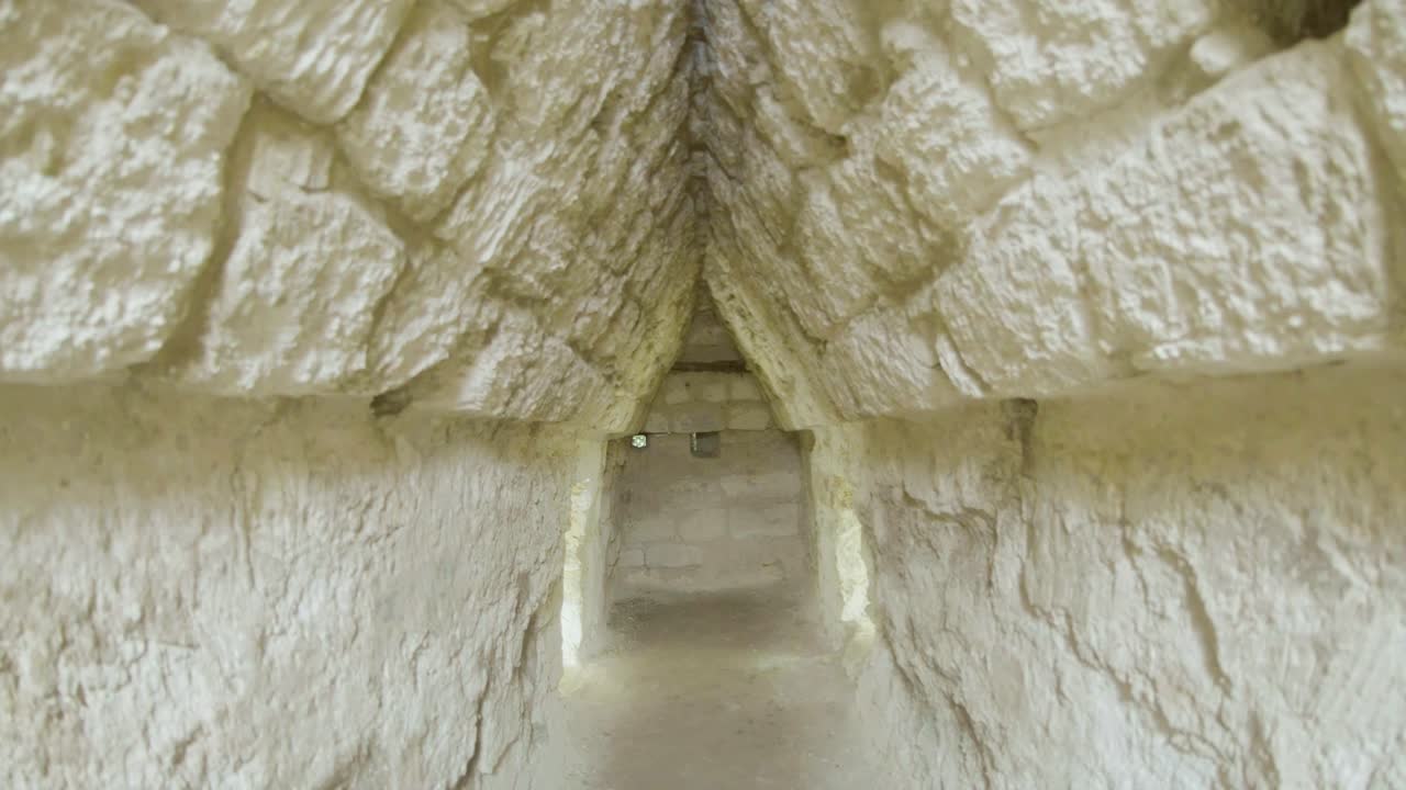 View of ancient Maya structures at La Muerta, a hidden archaeological site in the jungle of El Petén, Guatemala. The ruins are partially covered by forest, evoking mystery and lost civilization.
