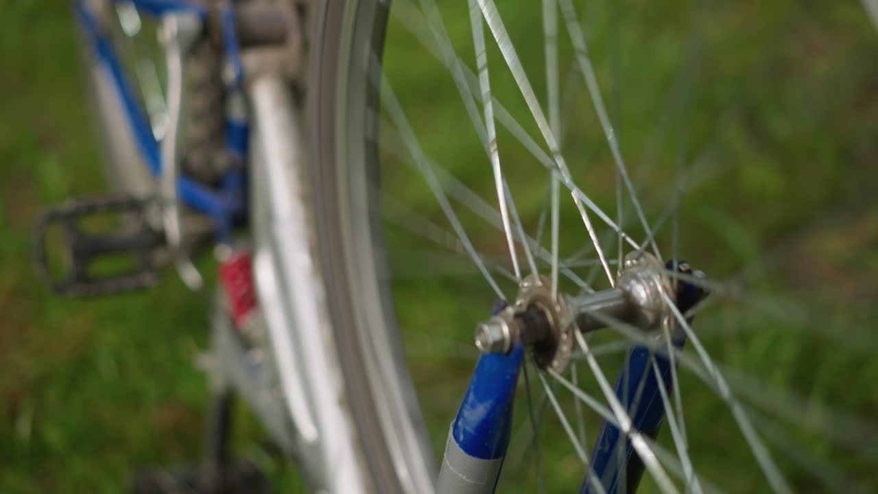 뒤쪽 타이어가 천천히 회전하는 자전거의 클로즈업, 초록색의 배경이 부드럽게 흐릿하게 남아있는 동안 바와 스피크에 초점을 맞추고 있습니다.