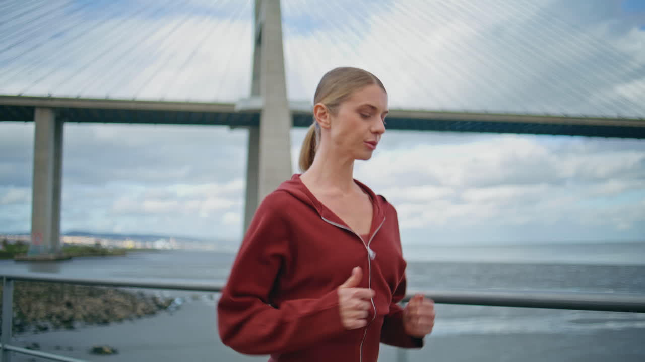 Smiling athlete running bridge view. Motivated girl do cardio workout