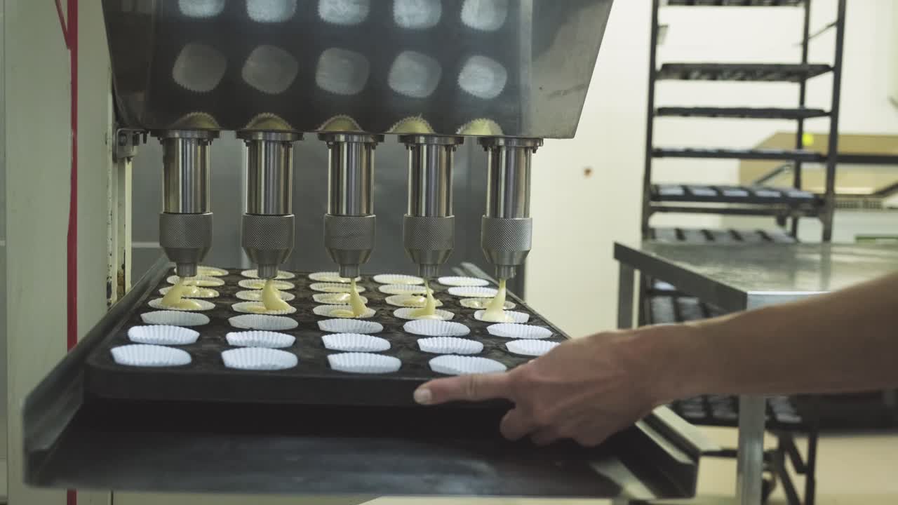 panadero anónimo en la preparación de muffins con máquina automática