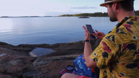 hombre de vacaciones usando un teléfono inteligente móvil, sobre el hombro vista