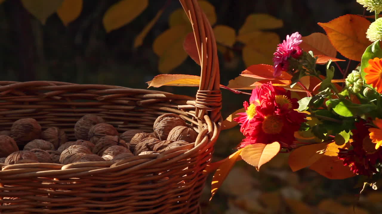 Cesto di vimini con noci accanto a fiori all'aperto su un tavolo