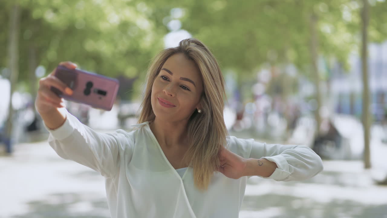 chica sonriente atractiva tomando una selfie al aire libre