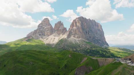 sassolungo mountain rises behind rolling green pastures and alpine trail in dolomites