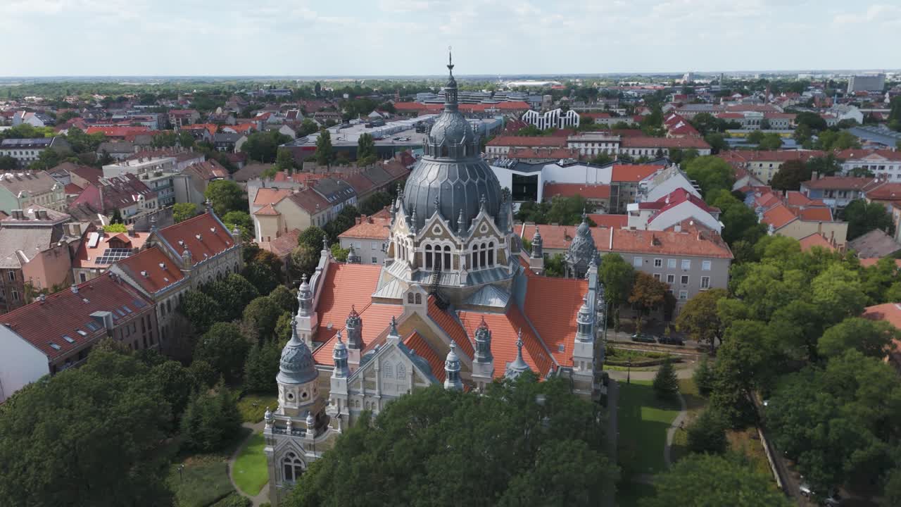 Ampia ripresa aerea orbitale del drone attorno alla sinagoga di Seghedino, che enfatizza i dettagli architettonici e il paesaggio urbano circostante