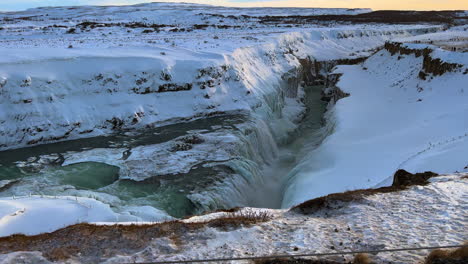 Gullfoss-Waterfall-Site-in-Winter,-Canyon-of-the-HvÃ­tÃ¡-River-Iceland,-Spectacular-View-from-Top-of-Water-Flow-Cascade-Descending-into-Canyon-Surrounded-by-Snow-Ice-and-Frozen-Lands,-Glacial-Landscape