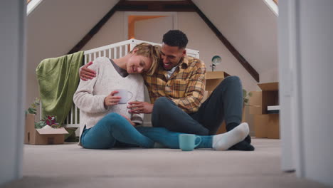 pareja esperando un bebé con bebidas calientes en la guardería de la nueva casa junto con la mudanza en cajas