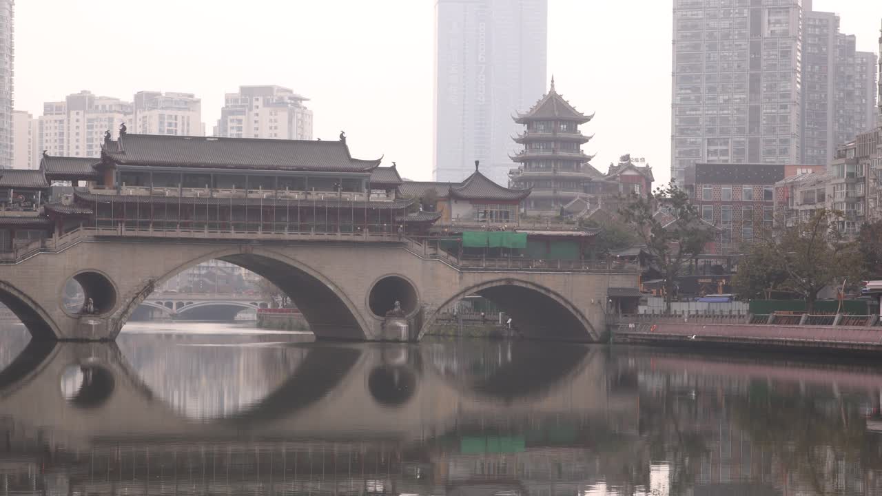 Chengdu capital city of the Chinese province of Sichuan, Anshun Bridge over the Jin river with modern skyline skyscraper building in background , ari pollution smog concept in metropolitan area