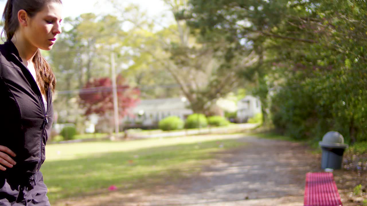 estirándose en un banco del parque, esta joven mujer atlética se prepara en silencio para una carrera vigorosa y ardua en el calor de georgia