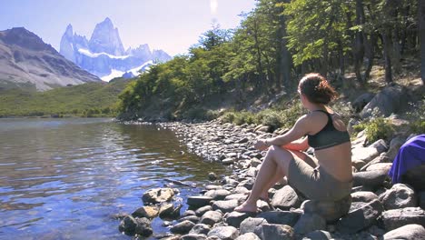 young woman sitting beside the lake in laguna carpi, looking at the fitz roy in patagonia, argentina