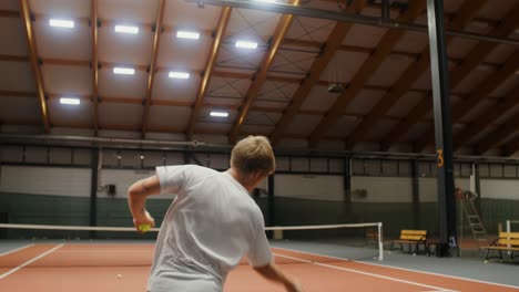 hombre jugando al tenis en una cancha cubierta