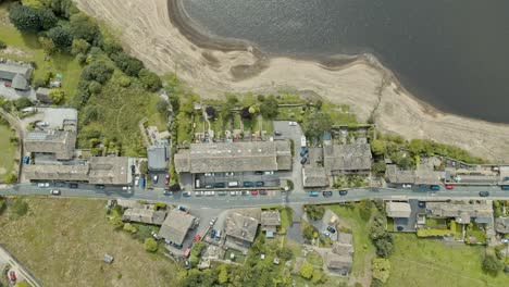 Aerial-footage-of-a-industrial-village-town-with-old-mill-and-chimney-stack-surrounded-by-fields