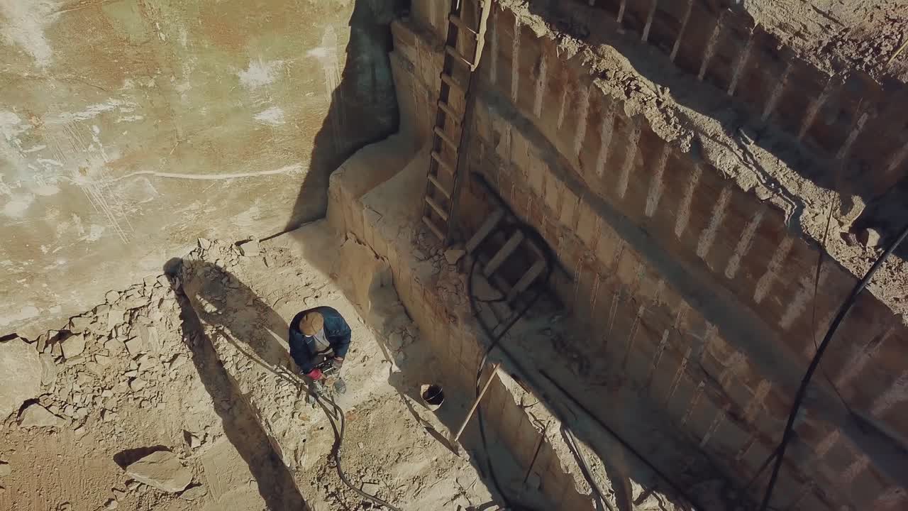 a man is drilling stones with using power tool in a sand quarry. Camera motion up