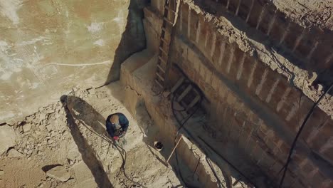 a man is drilling stones with using power tool in a sand quarry. camera motion up
