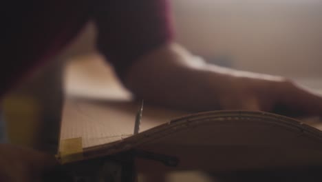a carpenter saws a skateboard out of a wooden board using a jigsaw