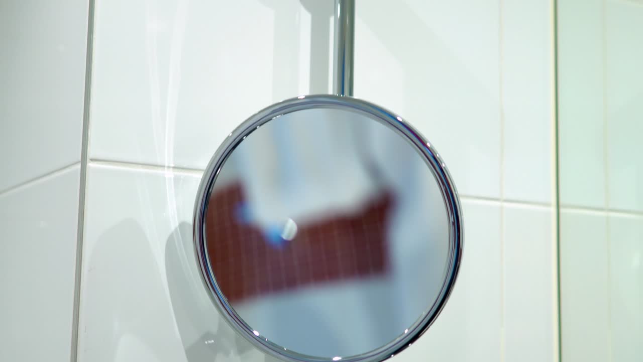 둥근 화장실 조절 가능한 거울 벽에 중간 부분이 절단 경로로 고립되어 있습니다.