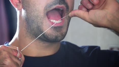 hombre que limpia los dientes con hilo dental