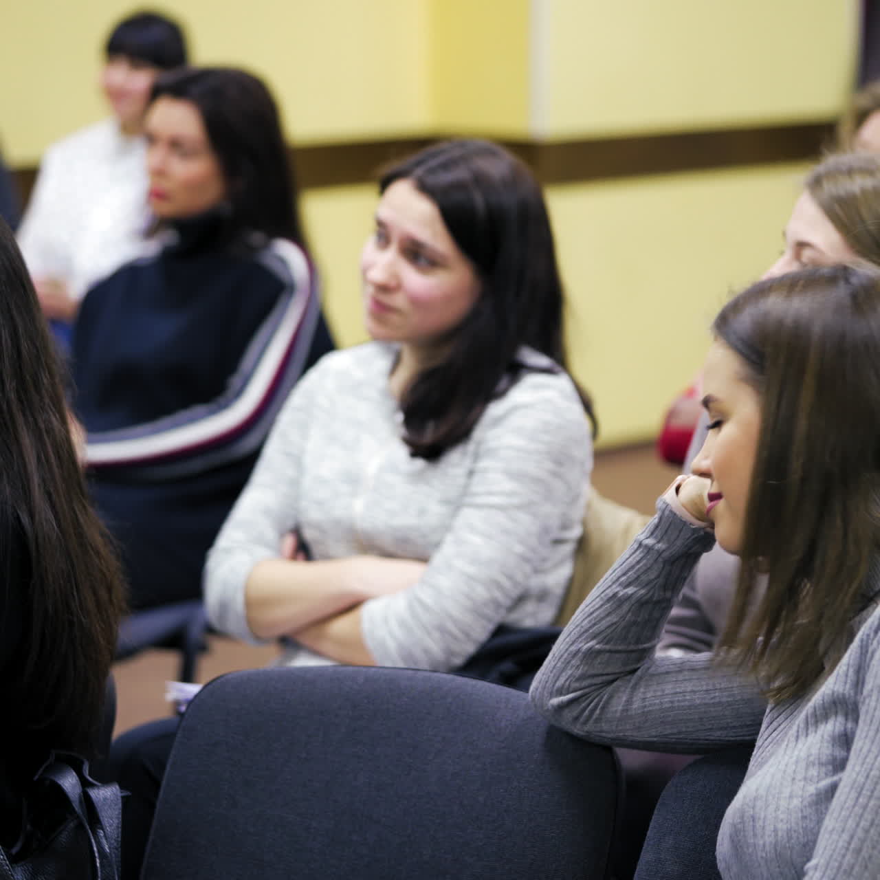 Female audience during the lecture. Attractive young women sitting in the conference hall and listen the speech of a manager.