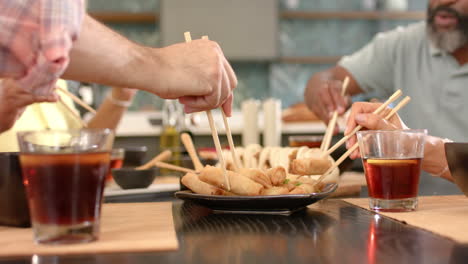 eating spring rolls with chopsticks, friends enjoying asian cuisine together