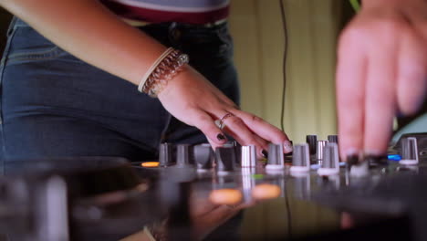 close-up of a dj with turning the knobs of the mixer